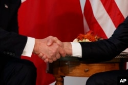 President Donald Trump shakes hands with French President Emmanuel Macron.