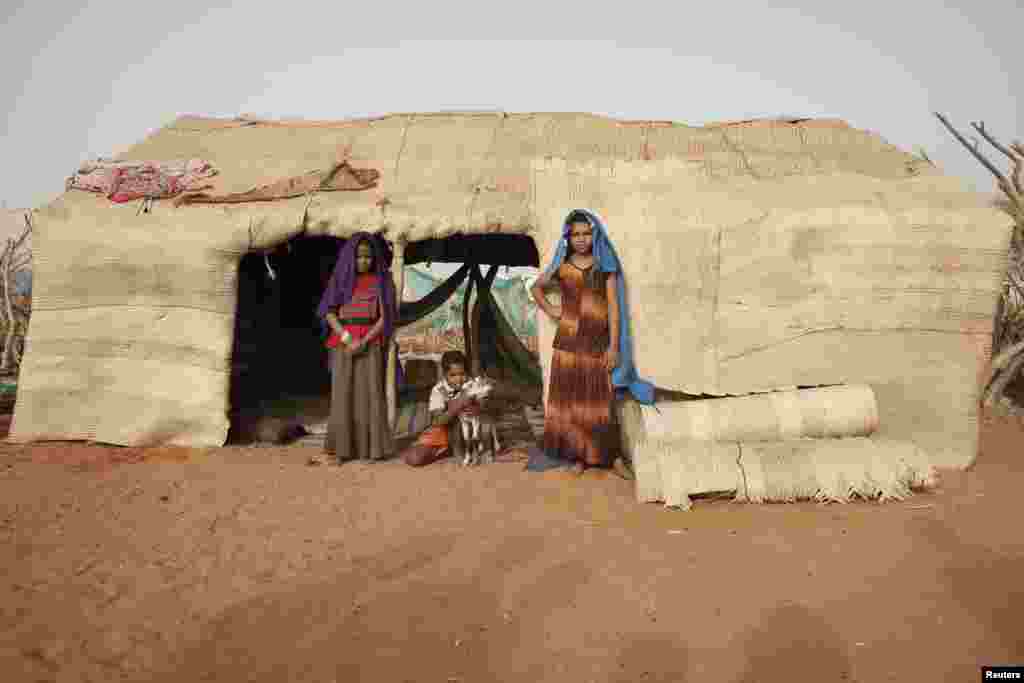 Les soeurs Aicha (à gauche) et Fatima Hamadi (à droite), et leur frère de 10 ans, Omar Ould Hamadi, devant leur abri dans le camp de Mbera. Ils ont fui Tombouctou au mois de mars en compagnie de leurs parents.