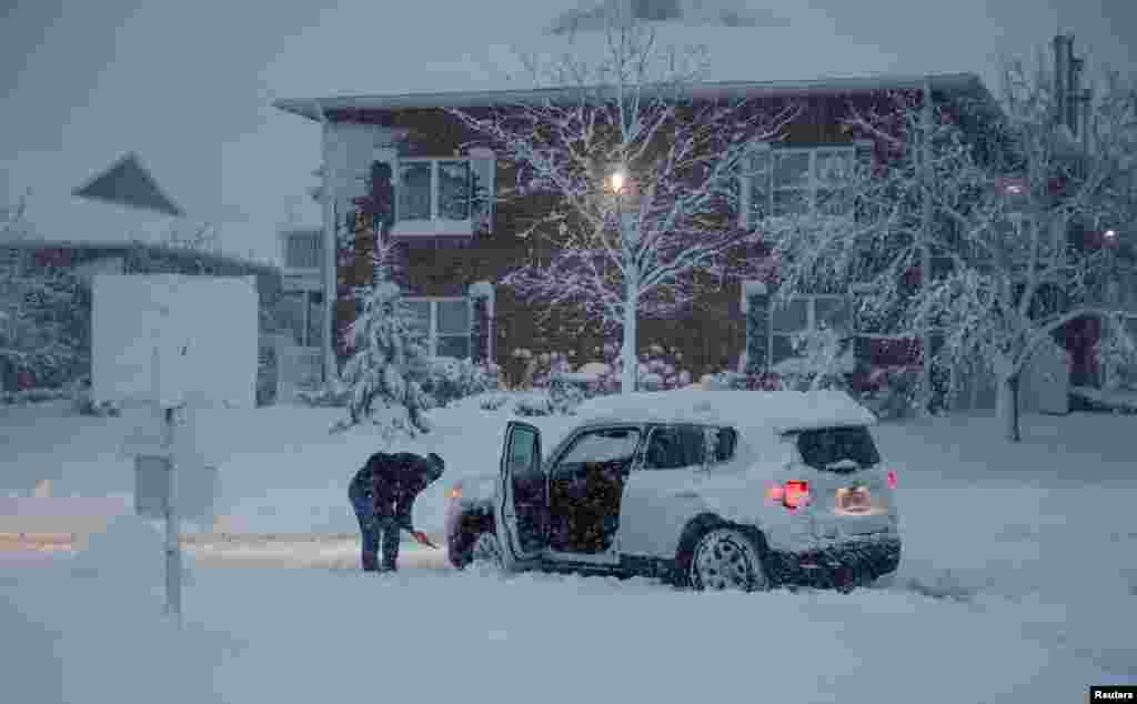 یک زن در حال پارو کردن برف از اطراف ماشین. او در توفان برف در بلندیهای آرلینگتون، ایالت ایلنیوی گرفتار شد.