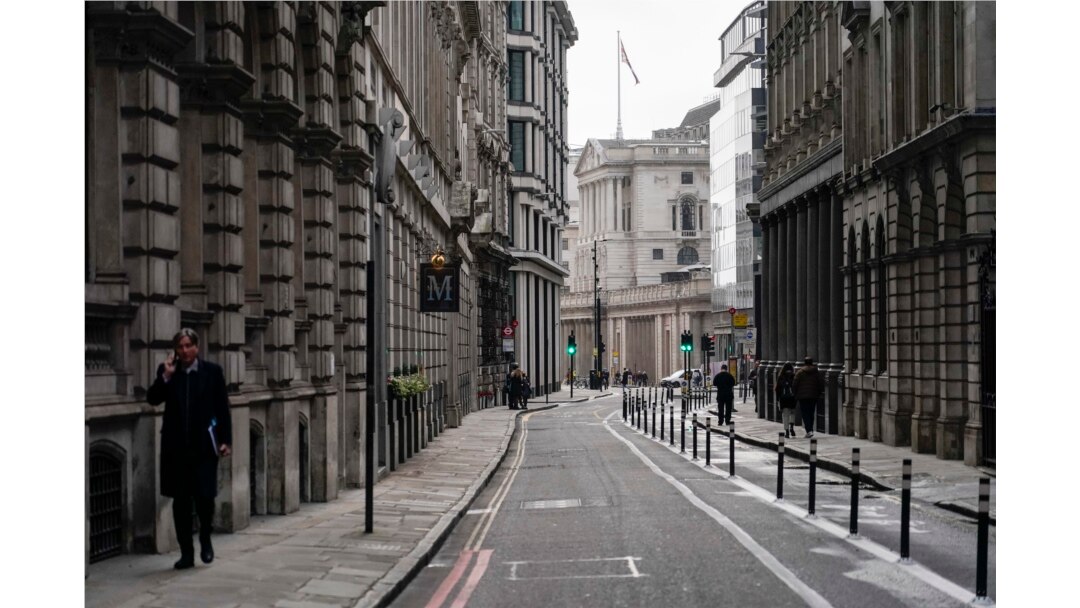 Seorang pria berbicara di telepon sambil berjalan di jalan kosong di distrik keuangan, yang dikenal sebagai The City, di London, Senin, 13 Desember 2021. (Foto: AP)