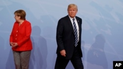 FILE - U.S. President Donald Trump walks off after being greeted by German Chancellor Angela Merkel after arriving at a G-20 Summit in Hamburg, Germany, July 7, 2017.