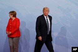 FILE - U.S. President Donald Trump walks off after being greeted by German Chancellor Angela Merkel after arriving at the G20 Summit in Hamburg, Germany, July 7, 2017.