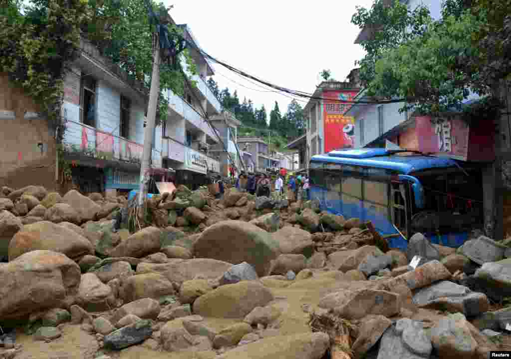 Penduduk desa berdiri di sebuah jalan yang rusak akibat hujan badai besar di kawasan Xuyong, Luzhou, provinsi Sichuan, China. Menurut media setempat, setidaknya 11 orang tewas, 13 orang hilang akibat hujan badai tersebut.