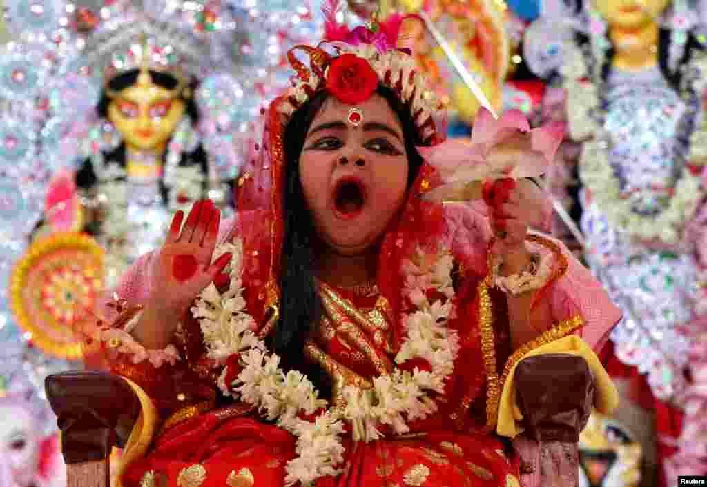 Nidhi Bhattacharjee, 5, dressed as a Kumari, yawns as she is worshipped by Hindu priests (unseen) as part of a ritual during the Durga Puja festival celebrations in Agartala, India.