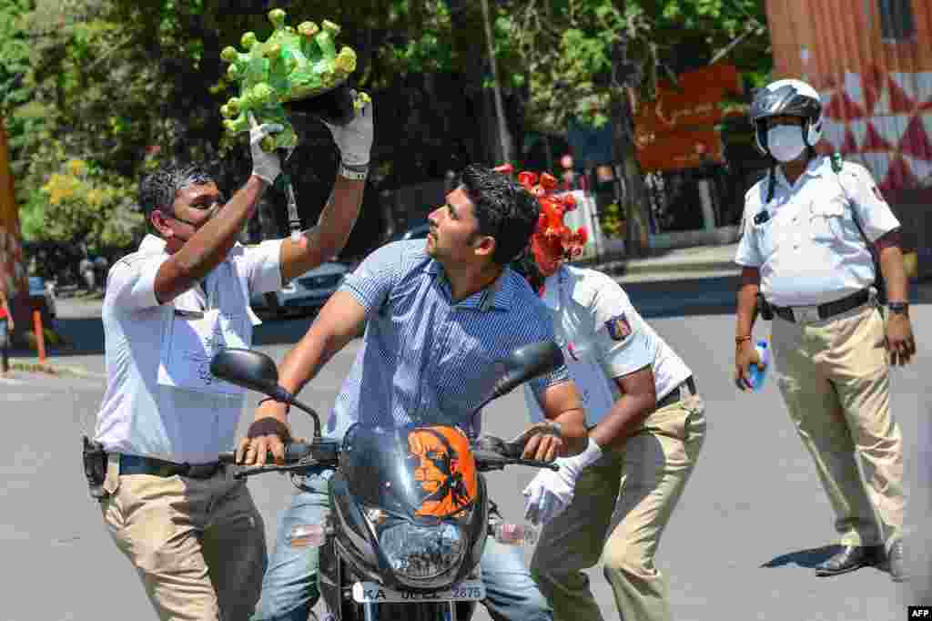 Traffic police personnel wearing coronavirus-themed helmets perform in front of a motorist (C) as they participate in a campaign to educate the public during a government-imposed nationwide lockdown.