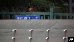 FILE - A Chinese paramilitary policeman stands watch behind a barrier leading to a side road outside the Japanese Embassy in Beijing, Sept. 30, 2015. 