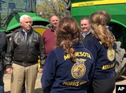 Vice President Mike Pence, left, visits with farmers and future farmers as he tours the R & J Johnson Farms in Glyndon, Minn., May 9, 2019, to talk about the Trump administration's trade agreement with Canada and Mexico.