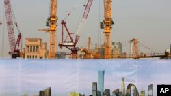 A construction area in Beijing is partly hidden by a billboard showing a view of many completed buildings.