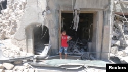 A boy stands at a site hit by a barrel bomb in the rebel-held area of Old Aleppo, Syria, July 11, 2016.