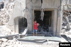 A boy stands at a site hit by a barrel bomb in the rebel-held area of Old Aleppo, Syria, July 11, 2016.