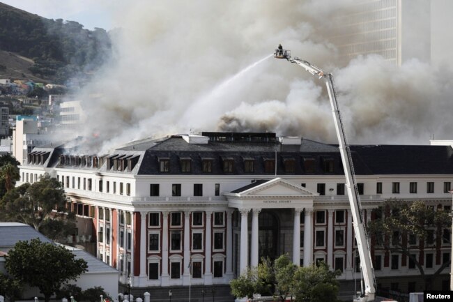 Firefighters work at the parliament as a fire flares up again, in Cape Town, South Africa, Jan. 3, 2022.