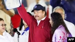 Foto publicada por la presidencia venezolana que muestra al presidente de Nicaragua, Daniel Ortega, mostrando un documento al prestar juramento como presidente por cuarto mandato consecutivo junto a su esposa y vicepresidenta, Rosario Murillo, el 10 de enero de 2022 en Managua.