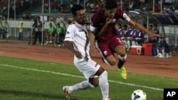 မြန်မာအသင်းက ထိုက်ထိုက်အောင် (ဝဲ) နဲ့ ကာတာအသင်းက Saltan Hussain M H Al-Brake တို့ ဘောလုံးလုနေစဉ်။ (အောက်တိုဘာ ၂၀၊ ၂၀၁၄) 