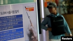 Seorang penumpang kereta api melewati layar televisi di stasiun kereta api Seoul, yang menayangkan berita terkait peluncuran misil dari kapal selam Korea Utara, 24 Agustus 2016 (Foto: REUTERS/Kim Hong-Ji)