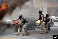 National police officers extinguish a burning vehicle that belongs to Radio Tele-Ginen during a protest in Port-au-Prince, June 10, 2019.