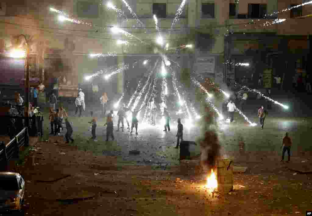 Kembang api dinyalakan oleh penentang Mohamed Morsi dalam bentrokan di pusat kota Kairo (15/7). (AP/Hussein Mala)