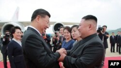 Pemimpin Korea Utara Kim Jong Un (kanan) berjabat tangan dengan Presiden China Xi Jinping setibanya di Bandara Iinternasional Pyongyang di Pyongyang. (Foto: KCNA via AFP)