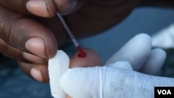Blood is taken from someone’s finger to test it for HIV at Bulungula, South Africa (D. Taylor/VOA)