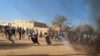 FILE - Sudanese demonstrators run from a teargas canister fired by riot policemen to disperse them as they participate in anti-government protests in Omdurman and Khartoum, Sudan, Jan. 20, 2019.