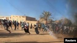 FILE - Sudanese demonstrators run from a teargas canister fired by riot policemen to disperse them as they participate in anti-government protests in Omdurman and Khartoum, Sudan, Jan. 20, 2019.