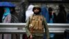 A policeman stands guard outside a polling station in Kabul as Afghans wanting to vote queue outside before it opens, April 5, 2014. 