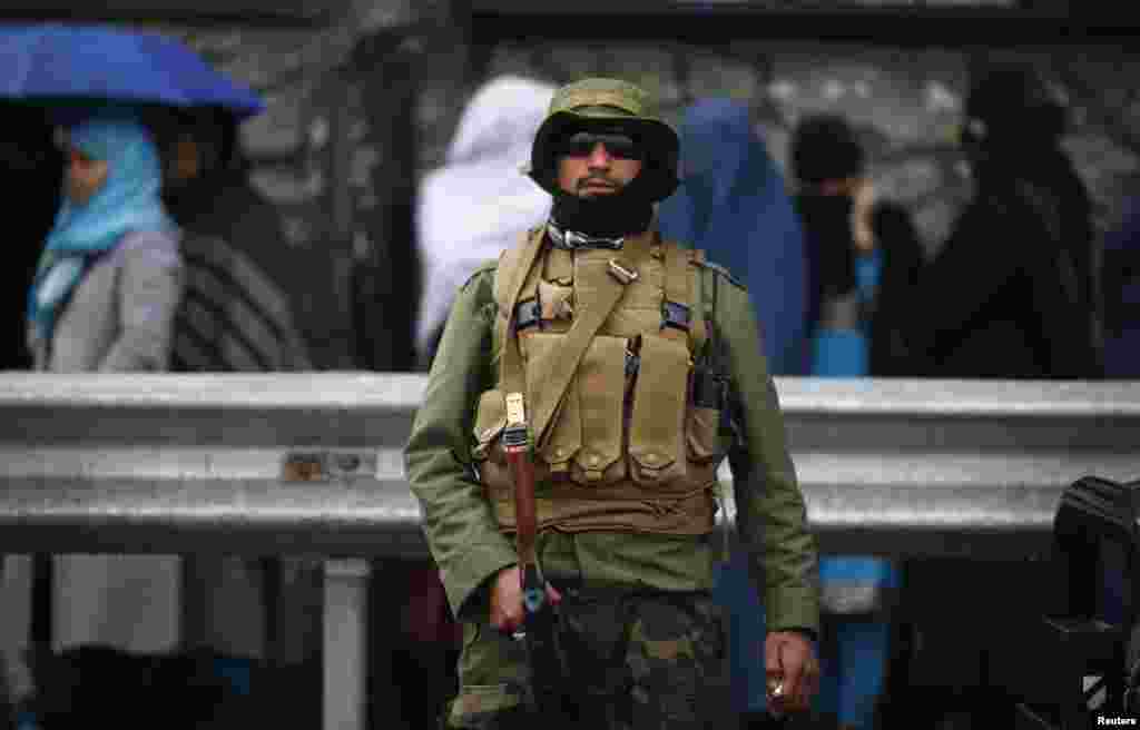 A policeman stands guard outside a polling station in Kabul as Afghans queue to vote outside before it opens.