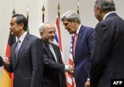 Iranian Foreign Minister Mohammad Javad Zarif (2nd L) shakes hands with U.S. Secretary of State John Kerry next to Chinese Foreign Minister Wang Yi (far L) and French Foreign Minister Laurent Fabius (far R) after a statement on early November 24, 2013 in