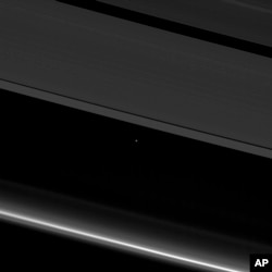 This April 12, 2017 image provided by NASA shows planet Earth and the moon, center left, as small points of light behind the rings of Saturn, captured by the Cassini spacecraft, 870 million miles (1.4 billion kilometers) away from Earth.