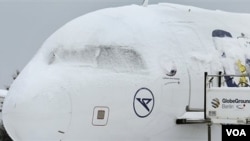 Salju besar menutupi pesawat terbang yang tengah parkir di bandara Schoenefeld di Berlin, Jerman, Senin 20 Desember 2010.