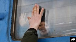 Dijete se oprašta od rođaka koji gleda kroz prozor vagona koji čeka da krene iz Ukrajine za zapadnu Ukrajinu na željezničkoj stanici u Kramatorsku, u istočnoj Ukrajini, 27. februara 2022.