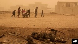 Un grupo de civiles pasan cerca del cuerpo de un militante de ISIS, mientras huyen de Mosul debido al intenso ataque del grupo extremista.