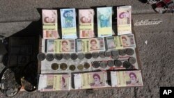 Iranian banknotes and foreign coins are displayed by a vendor on a Ferdowsi Street sidewalk in Tehran, Jan. 23, 2013.