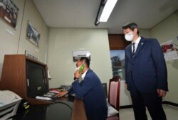 Seorang pejabat pemerintah Korea Selatan melakukan panggilan telepon ke Korea Utara melalui hotline komunikasi khusus saat Menteri Unifikasi Korea Selatan Lee In-young (kanan), mengawasinya saat meninjau kantor tersebut di Panmunjom, Zona Demiliterisasi, Korea Selatan, 16 September 2020.
