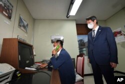 Seorang pejabat pemerintah Korea Selatan melakukan panggilan telepon ke Korea Utara melalui hotline komunikasi khusus saat Menteri Unifikasi Korea Selatan Lee In-young (kanan), mengawasinya saat meninjau kantor tersebut di Panmunjom, Zona Demiliterisasi, Korea Selatan, 16 September 2020.