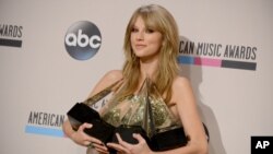 Taylor Swift berpose di belakang panggung dengan empat penghargaan yang diraihnya pada American Music Awards (24/11). (AP/Invision/Jordan Strauss)