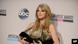 Taylor Swift poses backstage with the awards for favorite album - country for "Red", favorite female artist - pop/rock, favorite female artist - country, and artist of the year at the American Music Awards, Nov. 24, 2013, 
