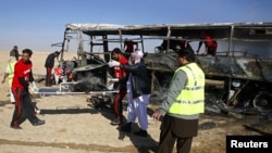 Para petugas mengangkat sisa-sisa jenazah para peziarah Syiah yang terbakar dari dalam bus di Quetta, Pakistan (30/12). Iring-iringan bis para peziarah Syiah ke Iran menjadi target bom yang diledakkan dari jarak jauh. Dilaporkan 20 orang tewas dan sedikitnya 24 terluka dalam insiden ini.