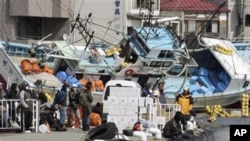 Local residents wait for a ship to travel to a nearby island from the devastated city of Kesennuma, northeastern Japan, just one week after a massive earthquake and resulting tsunami, March 18, 2011