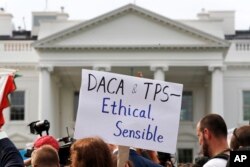 FILE - A person holds up a sign in support of the Deferred Action for Childhood Arrivals, known as DACA, and Temporary Protected Status programs during a rally in support of DACA and TPS outside of the White House, in Washington.