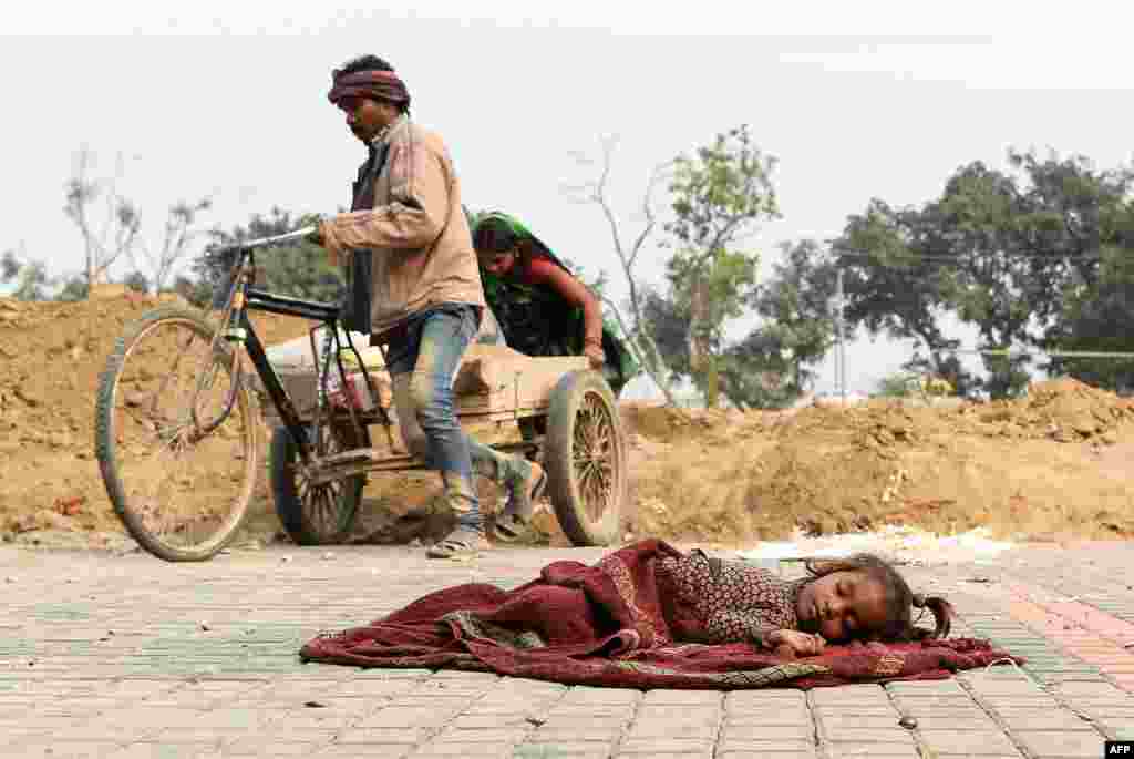 A child sleeps on a blanket near a construction site in New Delhi, India.