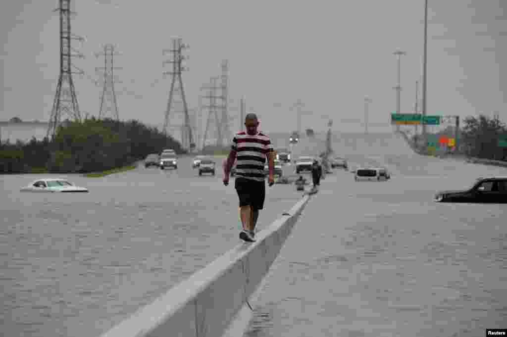 A stranded motorist escapes floodwaters on Interstate 225 after Hurricane Harvey inundated the Texas Gulf coast with rain causing mass flooding, in Houston, Texas, U.S. August 27, 2017. 