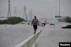 A stranded motorist escapes floodwaters on Interstate 225 after Hurricane Harvey inundated the Texas Gulf coast with rain causing mass flooding, in Houston, Texas, Aug. 27, 2017.