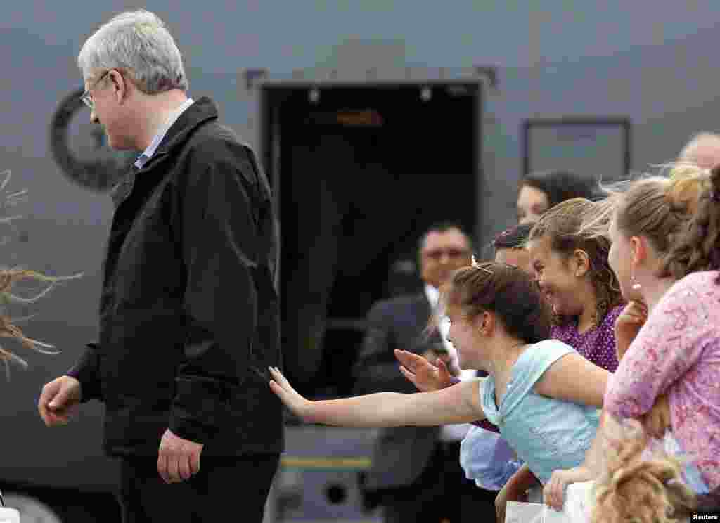 Brianna Goodwin, 9, reaches out to touch Canadian Prime Minister Stephen Harper as he greets children from a summer camp in Hay River, Northwest Territories, Aug. 19, 2013. 