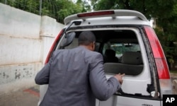 FILE - Abdiqadir Dulyar, director for the Somali television station Horn Cable, looks at the smashed window of a car that was carrying journalists working for his station in Mogadishu, May 3, 2016. Unidentified gunmen opened fire on the car.