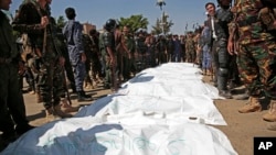 Police stand around bags containing the bodies of nine men, convicted in the killing of a senior Houthi official, after their executions in Sanaa, Yemen, Sept. 18, 2021.