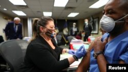 U.S. Army SSG Marvin Cornish is injected with a COVID-19 vaccine