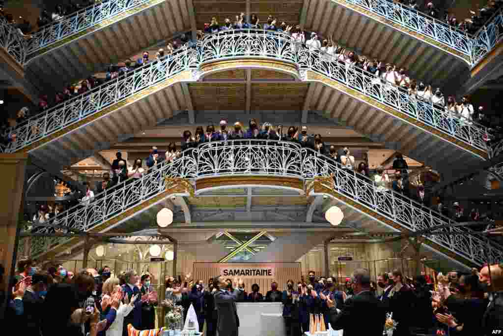 French President Emmanuel Macron (C) and employees of Paris&#39; iconic department store La Samaritaine applaud during a ceremony marking the store&#39;s reopening after 16 years of closure.