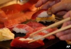 In this Sunday, Jan. 5, 2014 file photo, customers take sushi of a bluefin tuna which was bought by sushi restauranteur Kiyoshi Kimura (AP Photo/Shizuo Kambayashi, File)