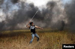 A Palestinian hurls stones at Israeli troops during a protest along Israel's border with Gaza, March 30, 2018.