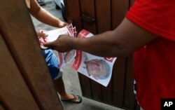 FILE - A man hands out campaign literature for Andres Manuel Lopez Obrador, in Acapulco, Mexico, June 19, 2018. The modern-day militarized drug fight, Lopez Obrador argued, has failed to stop narcotics smuggling and violence, and does not address the poverty that leads many to the drug trade.